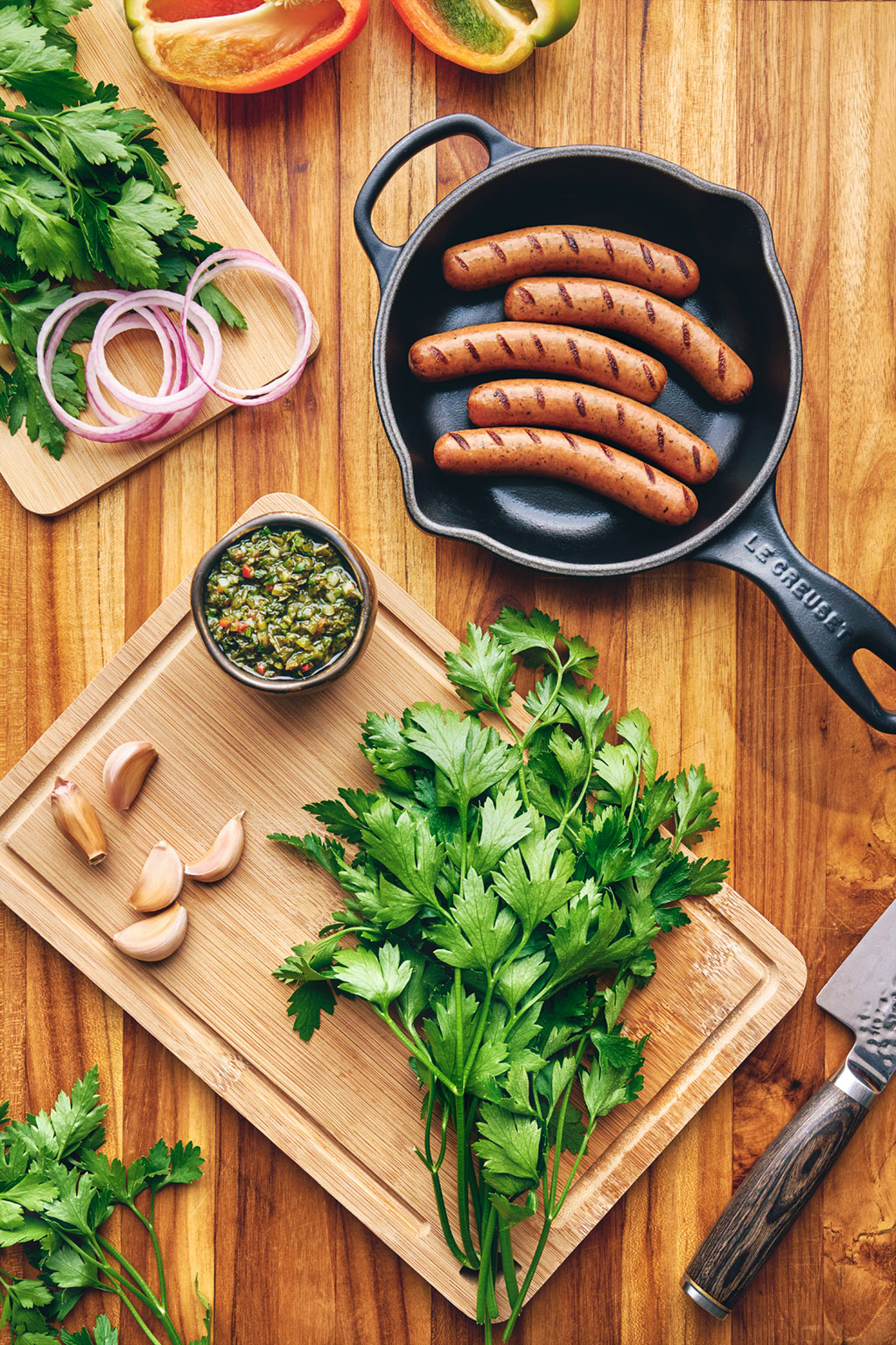 Overhead ranchera sausages in cast iron skillet with chimichurri