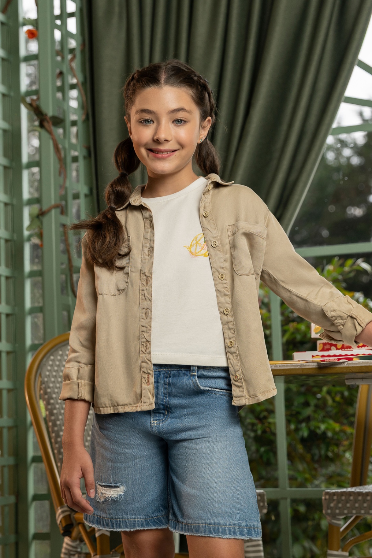 Young girl in beige overshirt and denim shorts in greenhouse