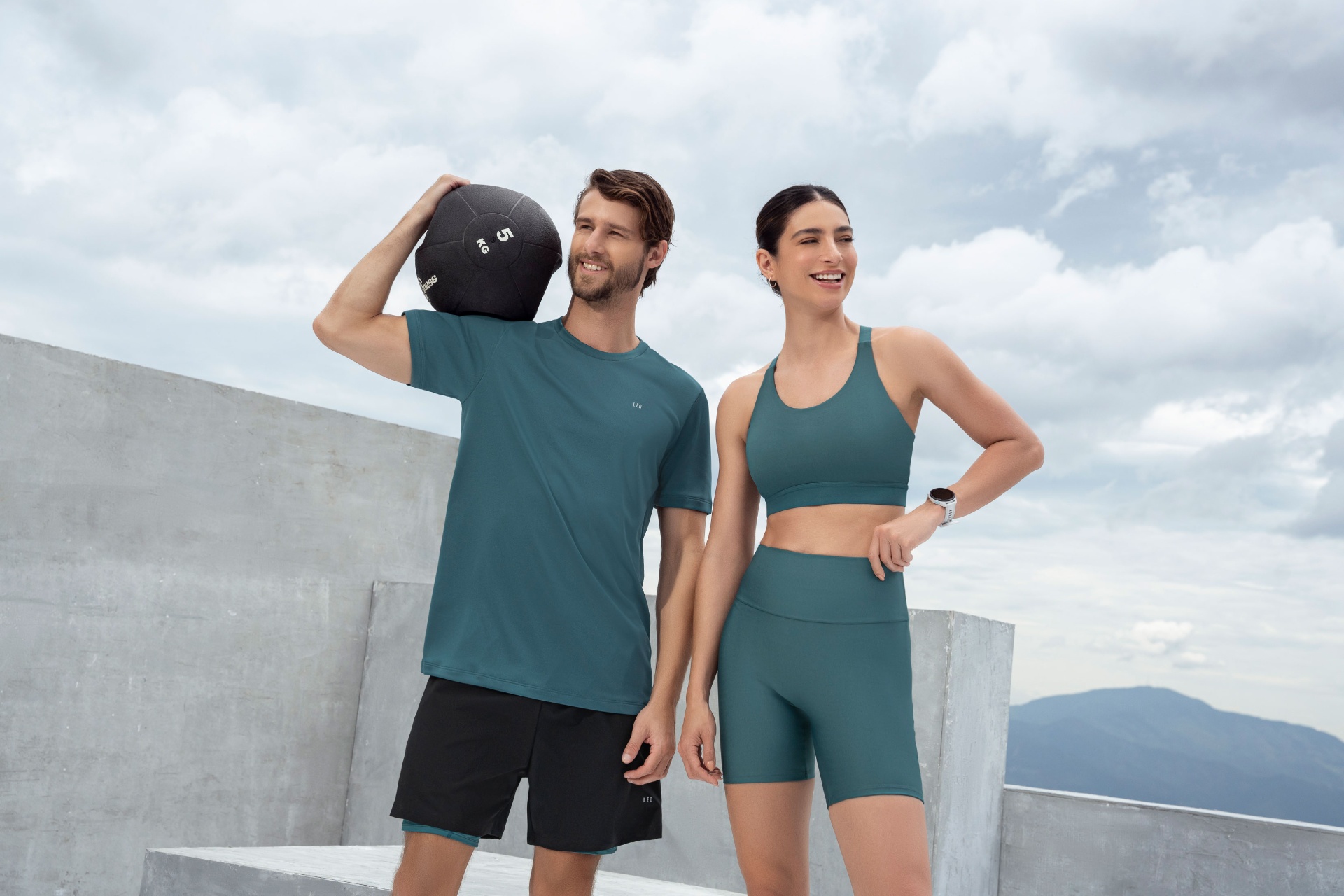 Couple training in teal sportswear on concrete rooftop