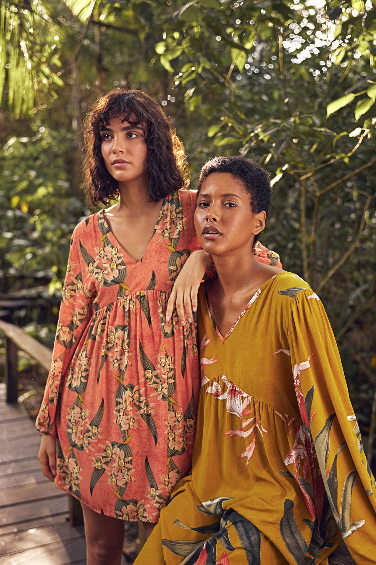 Two women in printed dresses on tropical boardwalk