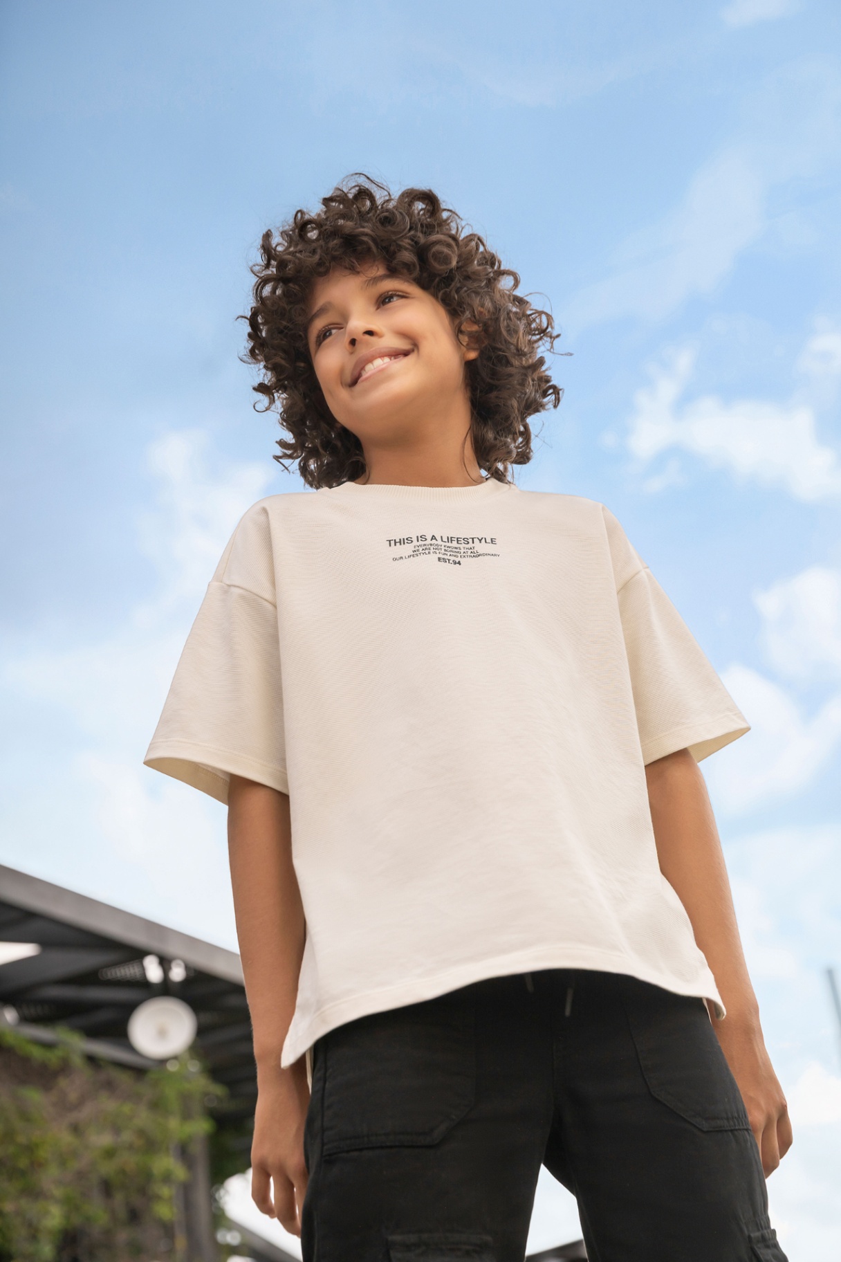 Boy in oversized tee against blue sky