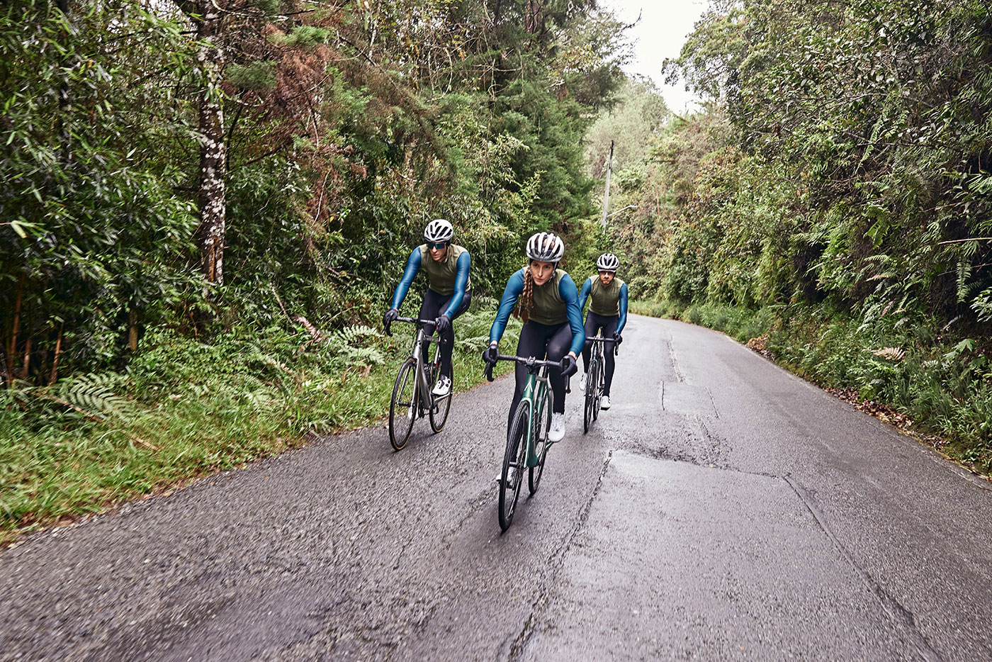 Three cyclists descending a forest road