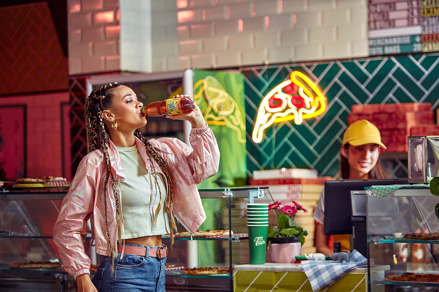 Woman drinking tea at neon-lit pizza counter