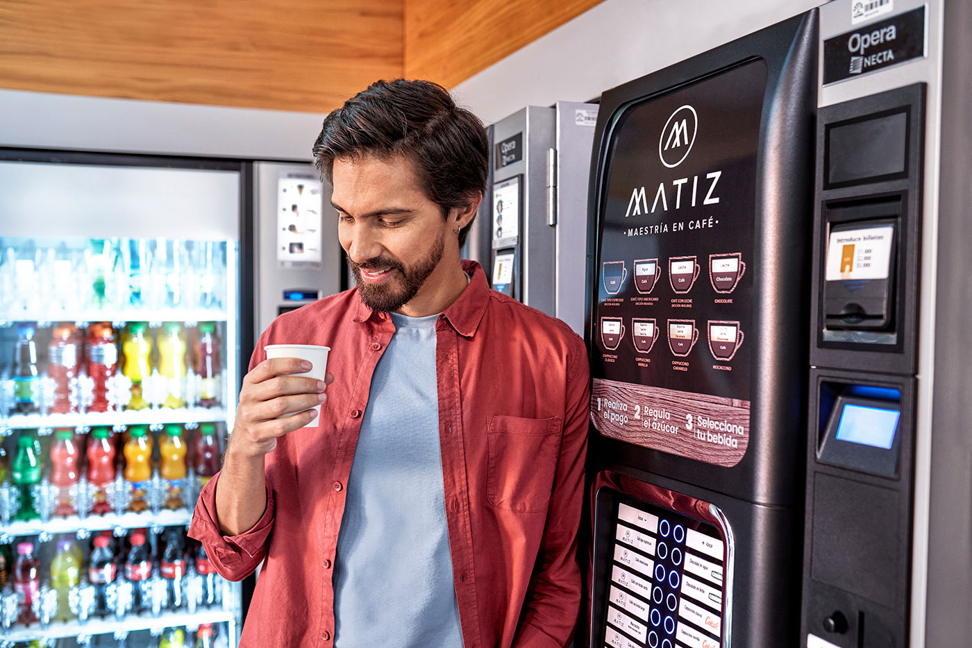 Man enjoying coffee next to Matiz vending machine